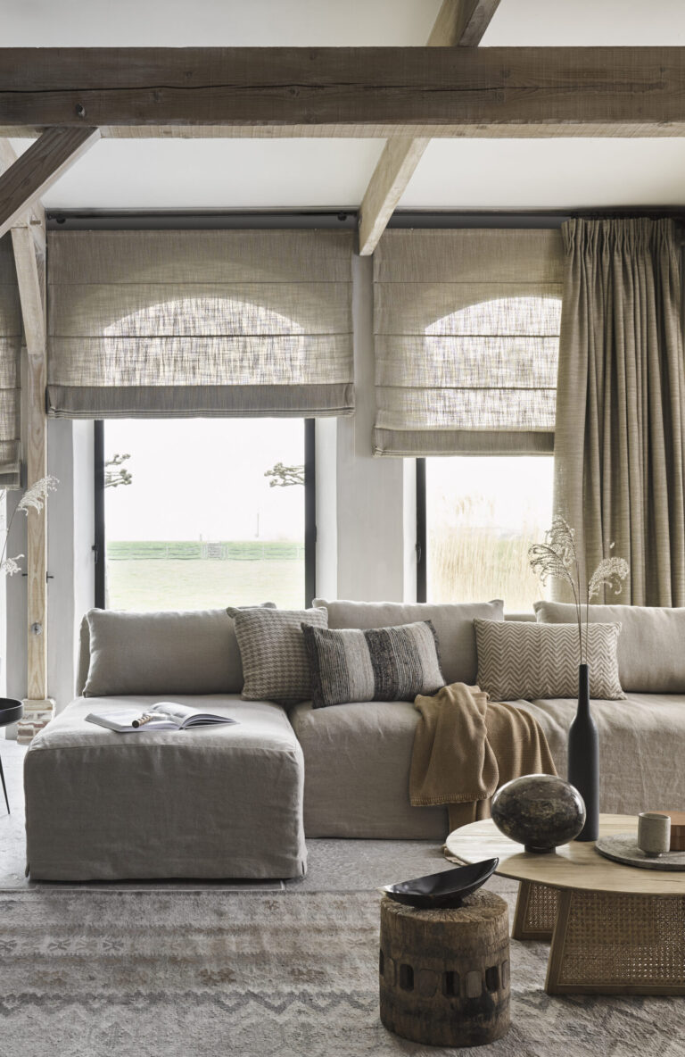 vouwgordijn en gordijn in woonkamer taupe bruine tinten hoebank